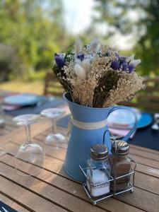 Un jarrón azul con flores en una mesa en Le Petit Bleu Chambre d'hôtes, en Bourg-de-Visa