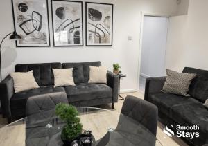 a living room with a black couch and a glass table at Contractors & Families 4 Bed House Sleeps 8 in Preston