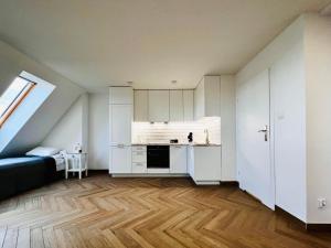 uma cozinha com armários brancos e piso em madeira em Apartamenty Kamienica Centrum em Lubin
