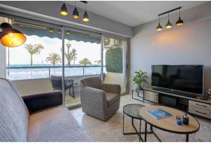 a living room with a couch and a television and a table at Flat design with SEA view promenade des anglais in Nice