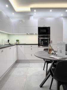 a kitchen with white cabinets and a table at Apartment K21 - Győr in Győr