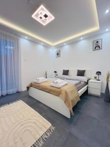 a white bedroom with two beds and a rug at Apartment K21 - Győr in Győr