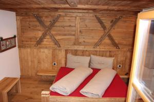 a bed in a room with a wooden wall at Almresidenz Unterrain zum Hartl -1 km BY CAR DISTANCE SKI SLOPES KRONPLATZ in Valdaora