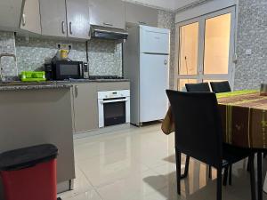 una cocina con electrodomésticos blancos y una mesa con sillas. en Have a fun in blida, en Dilida