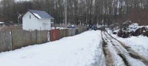 pokryta śniegiem ulica z ogrodzeniem i domem w obiekcie Happy Day Vendégház w mieście Kétbodony
