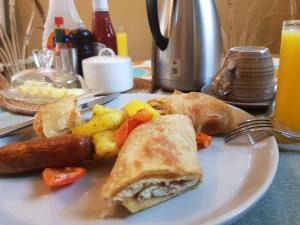 a white plate with a sandwich and sausage and vegetables at African Roots Gulu in Gulu