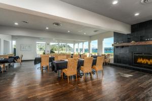 a dining room with tables and chairs and a fireplace at Alsi Resort Hotel in Waldport