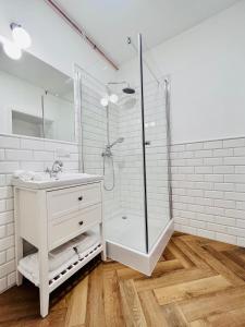 uma casa de banho branca com um chuveiro e um lavatório. em Apartamenty Kamienica Centrum em Lubin