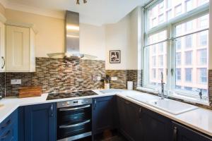 a kitchen with blue cabinets and a sink and a window at Stylish City Centre 2 Bed Apartment - Free Parking in Manchester