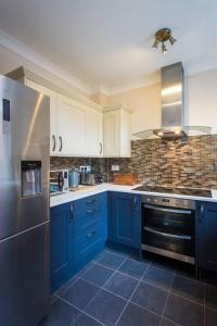 cocina con armarios azules y nevera de acero inoxidable en Stylish City Centre 2 Bed Apartment - Free Parking, en Mánchester