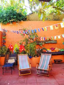 two lawn chairs and a fence with flags and plants at Pool House Hostel in Santa Ana