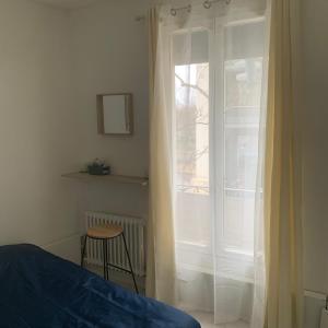 1 dormitorio con 1 cama y una ventana con cortinas en Hotel La Défense, en Colombes