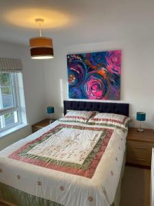 een slaapkamer met een bed met een schilderij aan de muur bij Modern 3bed house in central location & free parking in Aberdeen