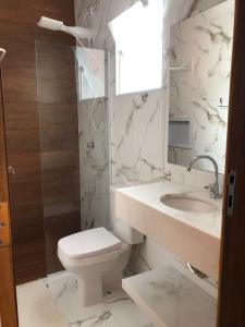 a white bathroom with a toilet and a sink at Pousada Refúgio das Flores in Ubatuba