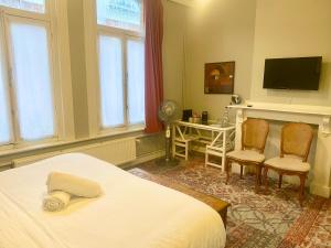 een slaapkamer met een bed en 2 stoelen en een bureau bij Simone's Kitchen B&B in Antwerpen