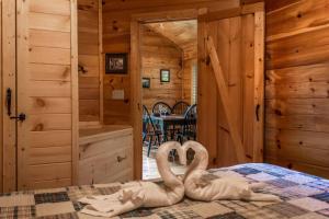 dos cisnes están sentados en una cama en una cabaña en Holly Tree Hideaway - Semi Secluded Mtn Setting en Sevierville