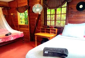 a bedroom with a bed and a desk and windows at La Familia Guest House and Natural Farm in Port Antonio