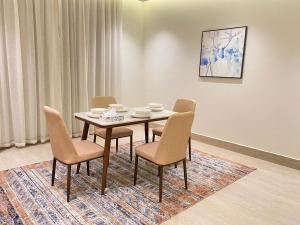 a dining room with a table and chairs on a rug at Nuzul R157 - Elegant Apartment in Riyadh