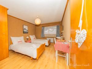 1 dormitorio con 2 camas, mesa y sofá en Hôtel l’escale, en Le Châble
