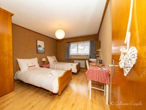 ein Hotelzimmer mit 2 Betten, einem Tisch und einem Schreibtisch in der Unterkunft Hôtel l’escale in Le Châble