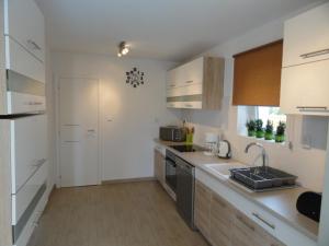 uma cozinha com armários brancos, um lavatório e um fogão em Villa KRK em Krk