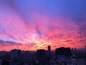una puesta de sol en una ciudad con nubes rojas en SkyView Oasis Premium Apartment en Tirana