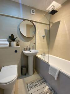 uma casa de banho com um WC, um lavatório e um espelho. em Stylish One Bedroom Flat Chancery Lane em Londres