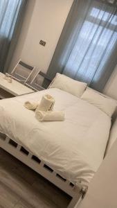 1 cama blanca grande con 2 toallas en Guest & Rest 14 en Londres