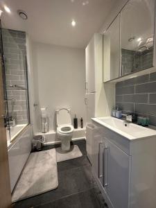 a white bathroom with a toilet and a sink at ABBA Heights in London