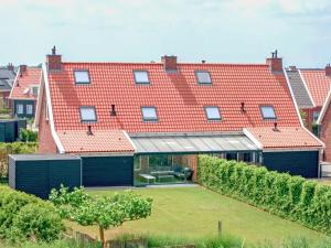 een groot huis met rode daken en een tuin bij Holiday home with whirlpool quiet area in Zeeland in Colijnsplaat