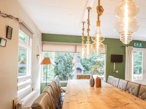 een eetkamer met een houten tafel en stoelen bij Beautiful home with lots of privacy, in the forest in De Bult