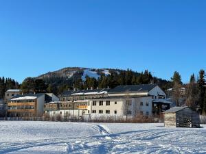 a large building in the middle of a snow covered field at Vandrarhemsboende på Ammarnäsgården in Ammarnäs