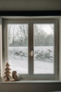 uma janela com uma árvore de Natal e um campo coberto de neve em Villa ADurbuy avec Jacuzzi em Durbuy