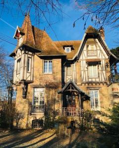 uma grande casa de tijolos com um telhado de gambrel em Studio au vert ! em Le Vésinet