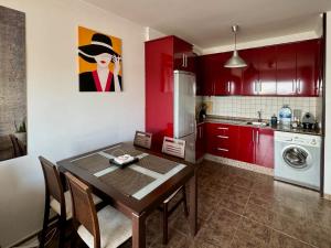 a kitchen with red cabinets and a dining room table at Iguazu I Yumbo Third Floor Apartment in Playa del Ingles