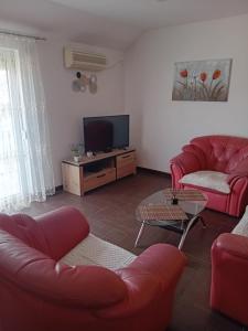 sala de estar con muebles de color rojo y TV de pantalla plana en Apartman M Batajnica, en Batajnica