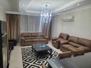 a living room with two couches and a chandelier at Logistic Apartment in Cairo