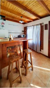 a kitchen with a wooden counter and two stools at La Herreria 2 in Esquel +4 photos