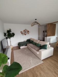 a living room with a white couch and green pillows at T4 spacieux+2 terrasse vue sur picine+parking gratuit in Gagnac-sur-Garonne