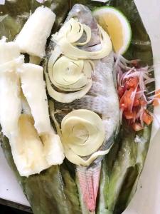 un plato con un pescado con cebolla y queso en Sacha Huasi, en Tena