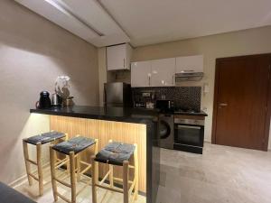 a kitchen with a counter and some stools in it at Studio sur golfe et piscine in Marrakesh