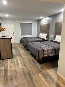 2 łóżka w pokoju hotelowym z drewnianą podłogą w obiekcie Continental Inn and Suites w mieście Nacogdoches