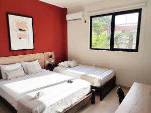 two beds in a room with red walls at Rua Hoteles Talara in Talara