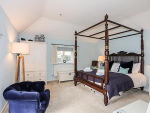 a bedroom with a canopy bed and a blue chair at Ty Siam in Newborough