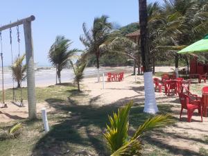 a beach with red chairs and tables and palm trees at COBERTURA Duplex com Visao do Mar, Village das ondas in Piúma