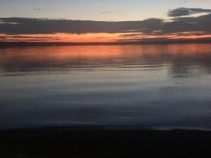 um pôr-do-sol sobre uma grande massa de água em Hässleholm med närhet till strövområde och sjö em Tormestorp