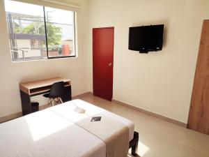 1 dormitorio con 1 cama y TV en la pared en Rua Hoteles Talara, en Talara