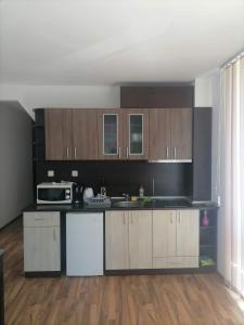 uma cozinha com armários de madeira e um micro-ondas em Двустаен апартамент em Sveti Vlas