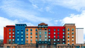 a group of colorful buildings with a cloudy sky in the background at Hotel María Bonita Chihuahua in Chihuahua