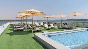 a pool with chairs and umbrellas next to the water at book Now Nile Cruise From Aswaon every Friday & Monday & wednesday Included Tours in Aswan